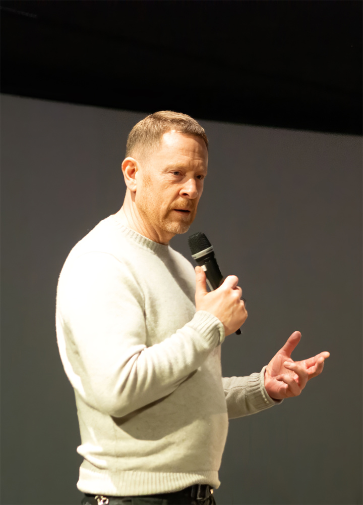 På bilden syns en man i äldre medelåldern vid namn Niklas Wahlström. Han jobbar på SFV. Han  är klädd i en beige tröja och har kort rött hår. Han står med en mikrofon i handen och tittar snett till höger. Bakgrunden är en mörk ridå.
