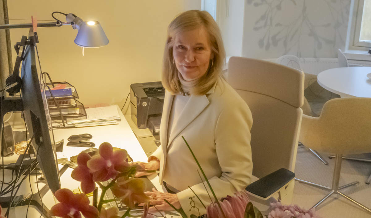 Camilla Nordblad vid datorn på SFV-kansliet i Helsingfors. framför hemme finns blommor hon fått.