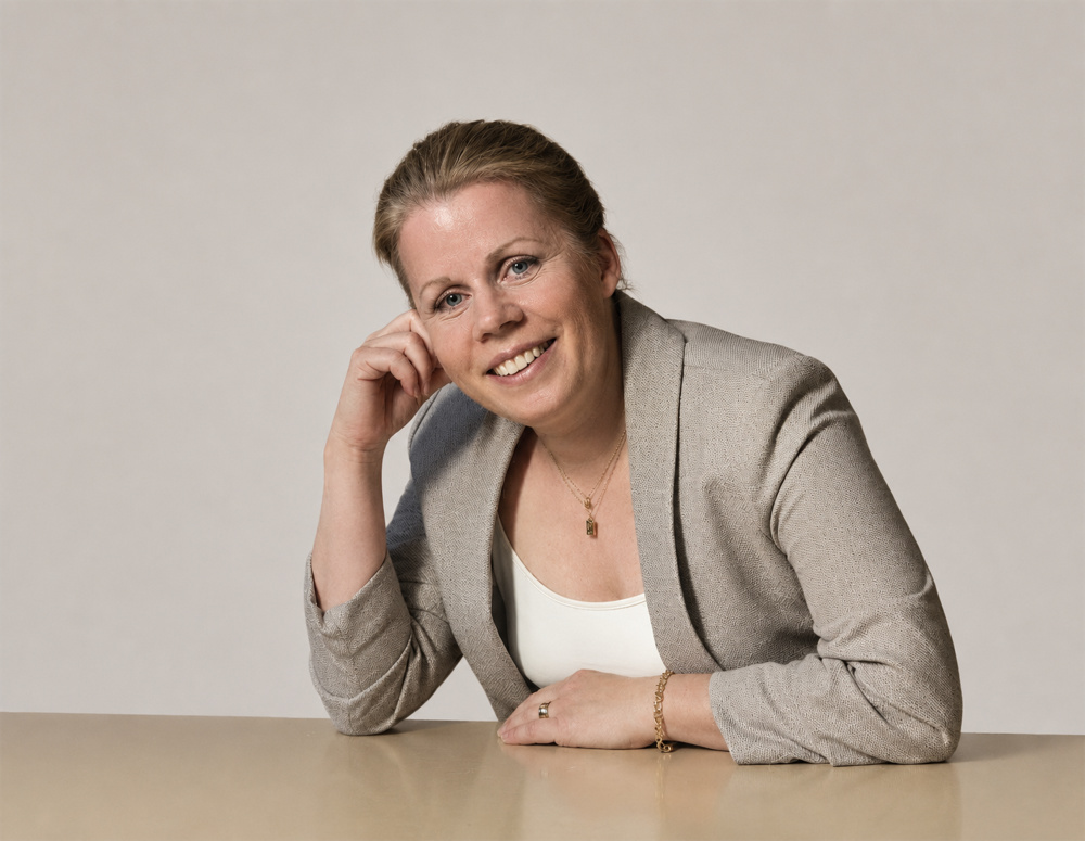 På bilden syns en medelålders kvinna vid namn Anna Tabelius Bodin. Hon har en ljugrå kavaj och en vit t-shirt under. Hon har ljust hår som är draget bort från ansiktet, hon tittar rakt in i kameran och ler. Hon lutar huvudet i handen som vilar på ett ljust bord. Bakgrunden är beige.