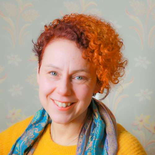 En leende Marjo Fränti har rött hår och färgranna kläder